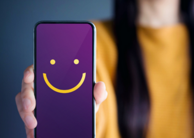 woman holding mobile phone with smiley face displaying